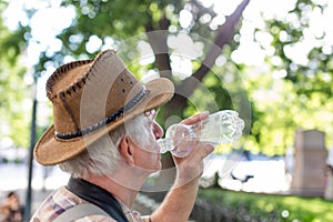 Senior thirsty tourist man drinking water from bottle