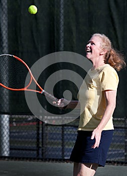 Senior tosses tennis ball and enjoys the game