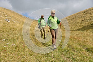 Senior tourist couple hiking at the beautiful mountains