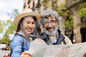 Senior tourist couple looking for location on city map