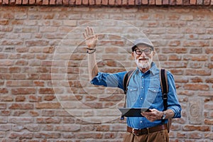 Senior tourist exploring new city, interesting places. Elderly man holding tablet and looking for the route. Traveling