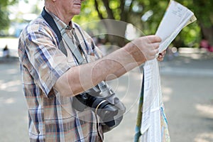 Senior tourist man with map and camera in public park