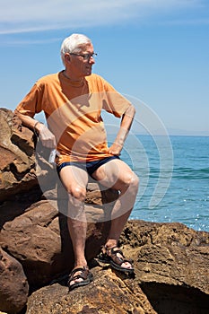 Senior tourist man on the rocky beach