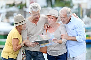 Senior tourists looking at map and tablet in town
