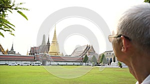 Senior travel toWat Phra Kaew, Grand palace, Temple of the Emerald Buddha with sky and green lawn. Landmark of Bangkok Thailand