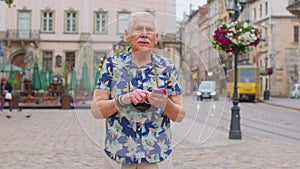 Senior traveler man grandfather pensioner getting lost in city, trying to find route on mobile phone