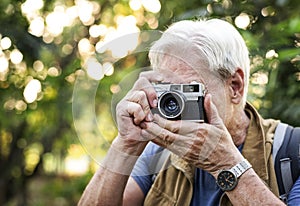 Senior trekker taking a photo with a film camera