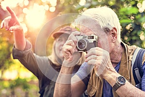 Senior trekker taking a photo with a film camera