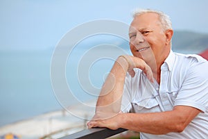 Senior on veranda, lean elbows about handrail photo