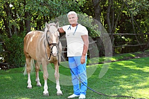 Senior veterinarian with palomino horse on sunny day