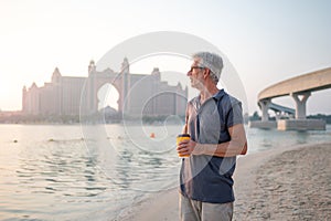 Senior visiting Palm Jumeirah in Dubai standing on the public beach