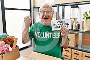 Senior volunteer man holding your donation matters screaming proud, celebrating victory and success very excited with raised arms