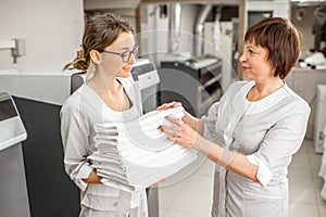 Senior washwoman with young assistant in the laundry
