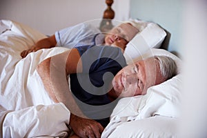 Senior white couple asleep in their bed, waist up, close up