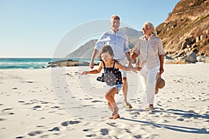 Senior white couple and their granddaughter walking on a sunny beach, close up