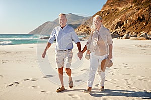 Senior white couple walking on a beach together holding hands, full length, close up