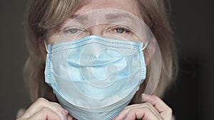 Senior white woman putting medical mask on her face