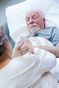 Senior wife giving glass of water to her sick husband