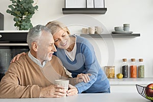 Senior wife snuggling up to husband while drinking tea