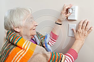 Senior woman adjusting her thermostat