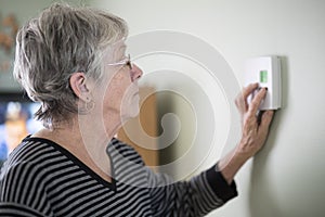 Senior woman adjusting her thermostat