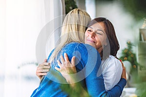 Senior woman with adult daughter at home at Christmas time, hugging.