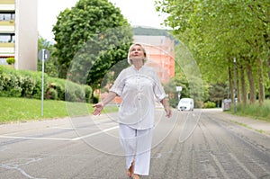 Senior Woman in All White Walking at the Street