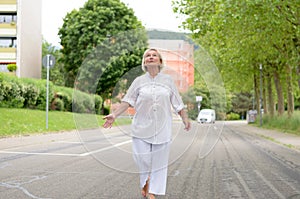 Senior Woman in All White Walking at the Street photo