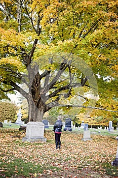 Senior woman alone at grave in cemetery