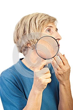 Senior woman analyze her wrinkles with loupe