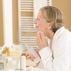 Senior woman apply face cleaning lotion