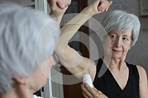 Senior woman applying deodorant in the bathroom