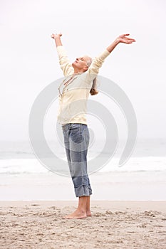 Senior Woman With Arms Outstretched On Beach photo