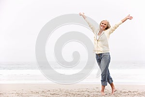 Senior Woman With Arms Outstretched On Beach photo