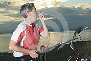 Senior woman with asthma inhalator on bike at the photo