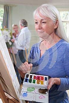 Senior Woman Attending Painting Class With Teacher In Background