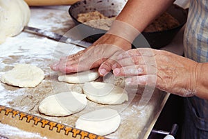 Senior woman baking pies in her home kitchen.Grandma cooks pies. Home cooked food. omemade mold cakes of the dough in the women`s