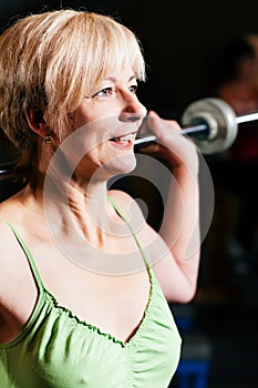 Senior Woman with barbell in gym