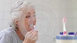 Senior Woman In Bathroom Brushing Teeth