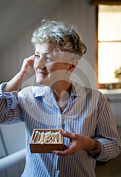 Senior woman in bathroom using ear cleaning sticks at home, ecologic and sustainable lifestyle.