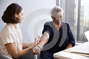 Senior Woman Being Vaccinated With Flu Jab By Female Doctor In Hospital Office photo