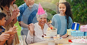 Senior woman, birthday cake and family in garden with applause, celebration and happy together for party. Man, women and