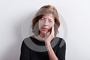 Senior woman in black t-shirt, studio shot against white wall.