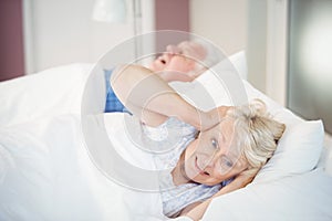 Senior woman blocking ears while man snoring on bed
