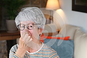 Senior woman blocking nose from unpleasant smell