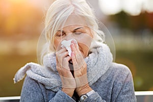 Senior woman blowing her nose