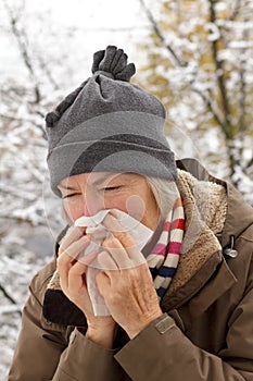 Senior woman blowing nose winter