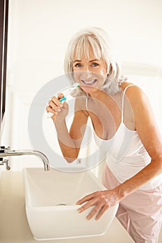 Senior Woman Brushing Teeth In Bathroom