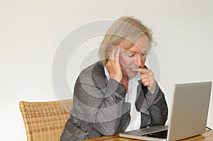 Senior woman in business look in front of a silver laptop