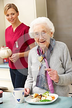 Senior woman with carer eating meal at home